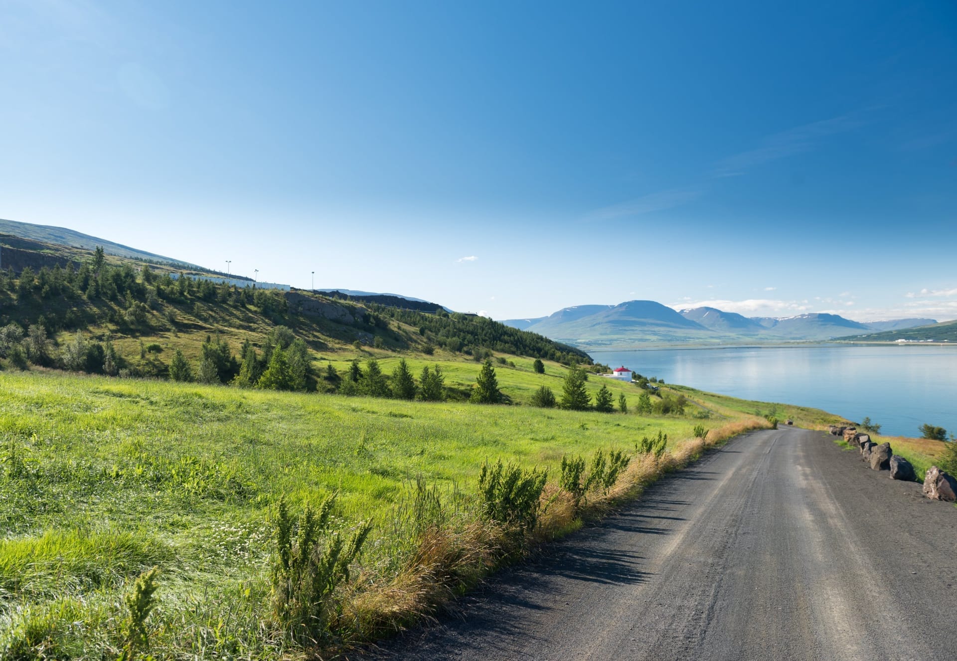 Blick über den Eyjafjörður auf Akureyri mit der Akureyrarkirkja und schneebedeckten Bergen im Hintergrund