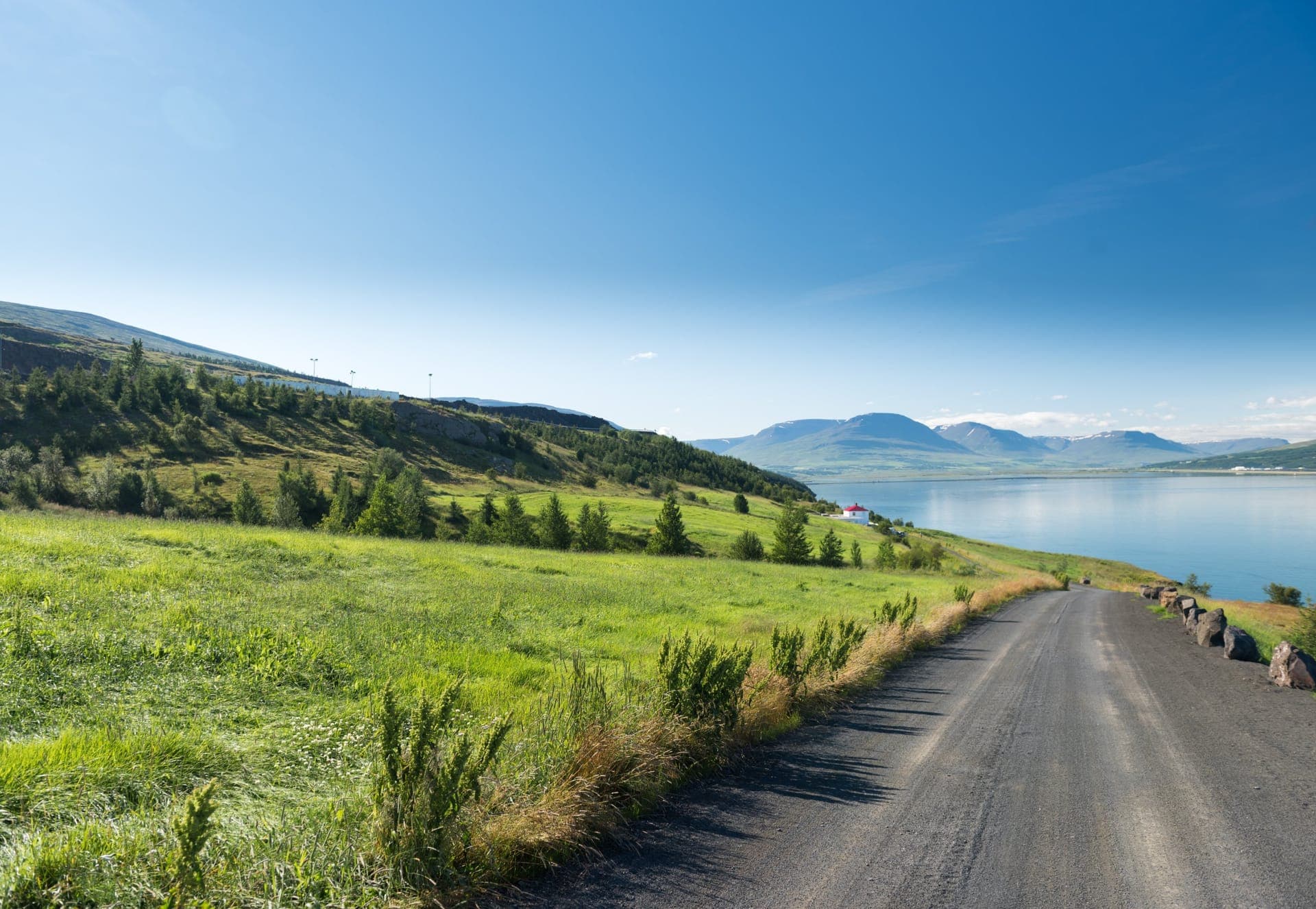 Blick über den Eyjafjörður auf Akureyri mit der Akureyrarkirkja und schneebedeckten Bergen im Hintergrund