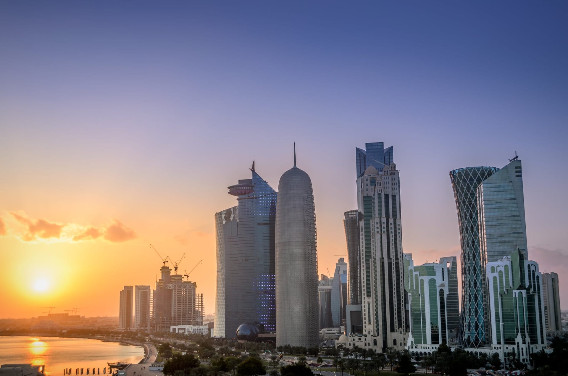 Die Wolkenkratzer der West Bay von Doha im Gegenlicht des Sonnenuntergangs, links die Bucht der Corniche