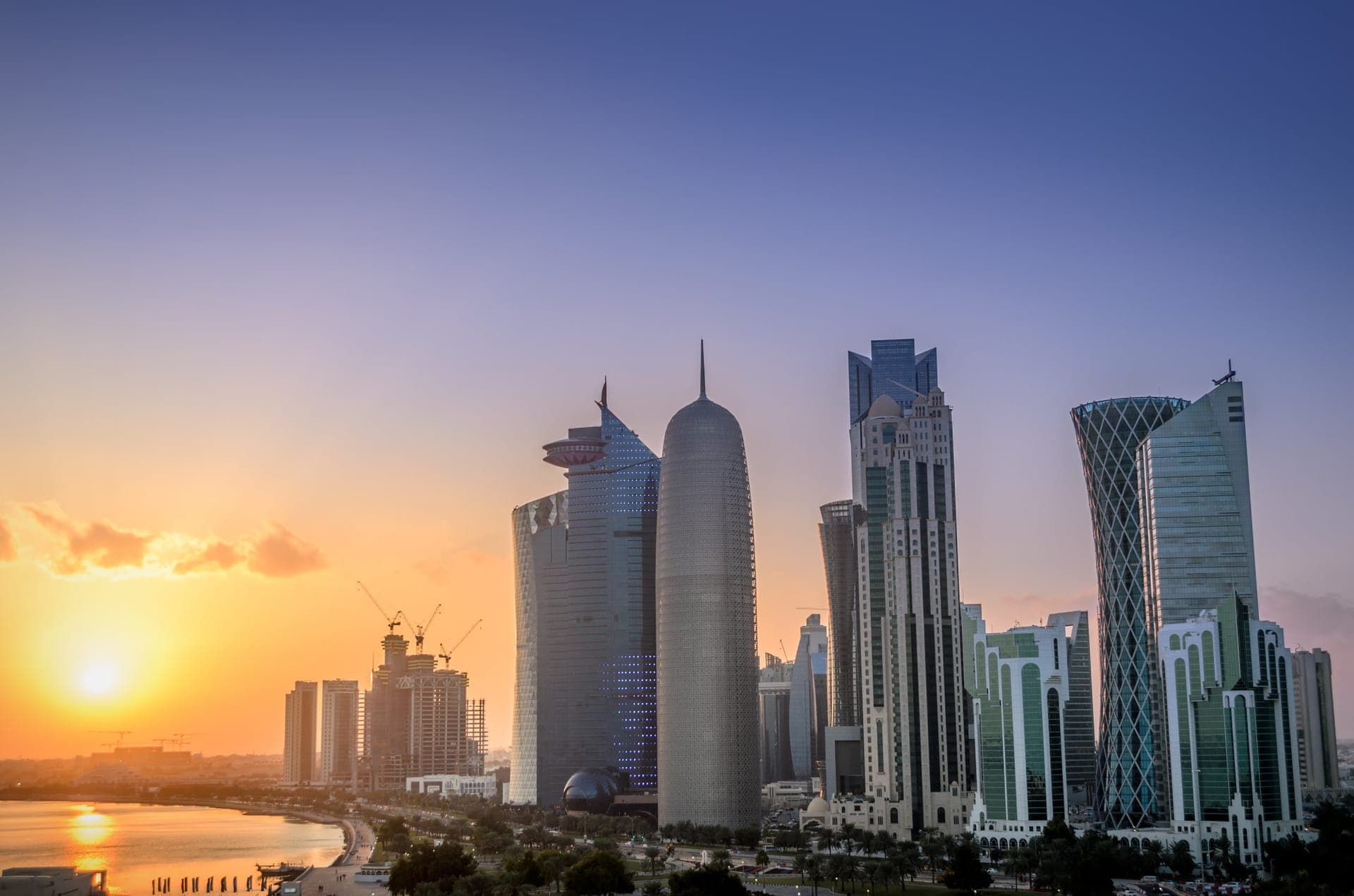 Die Wolkenkratzer der West Bay von Doha im Gegenlicht des Sonnenuntergangs, links die Bucht der Corniche