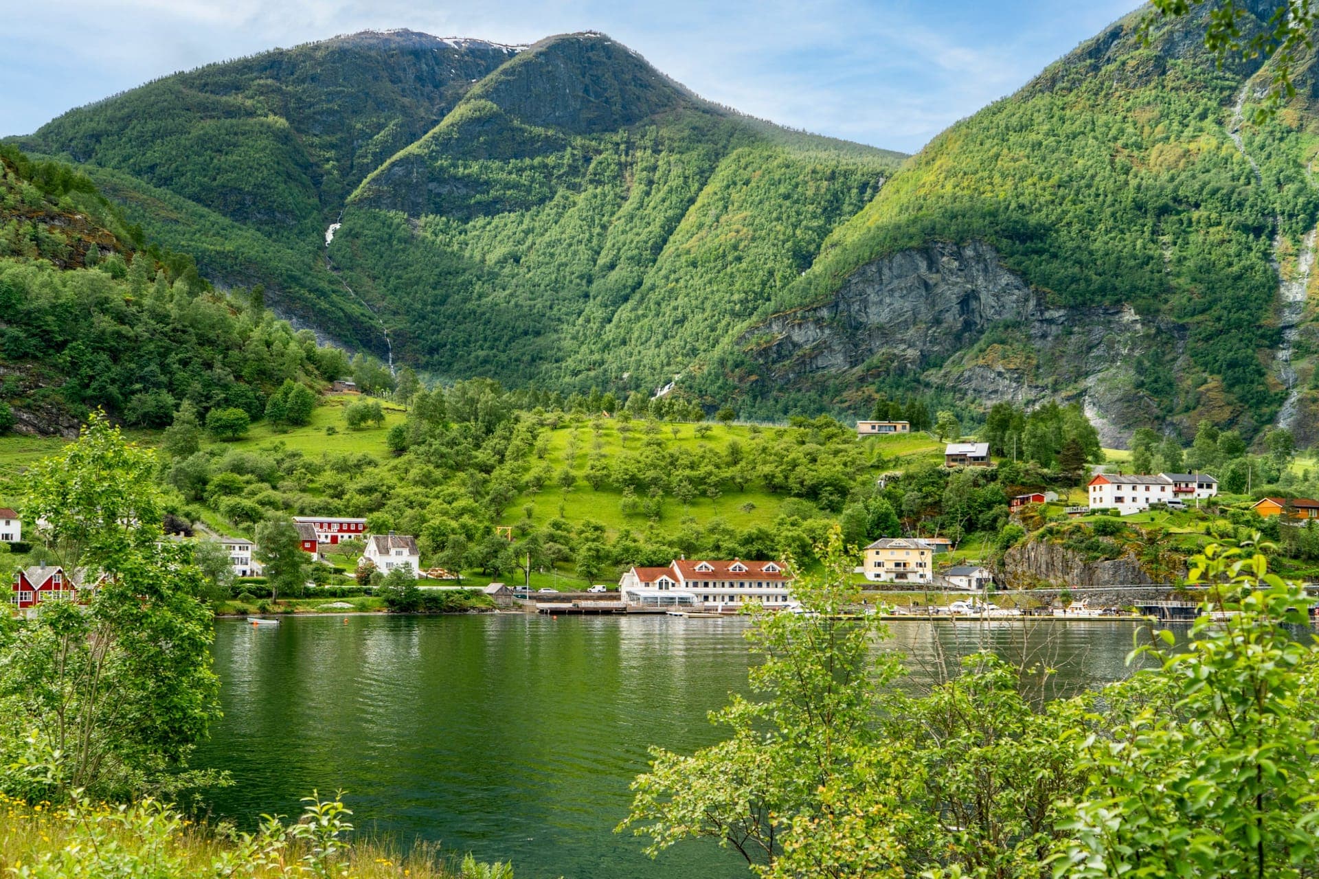 Das Fjorddorf Flåm mit grünen Berghängen am Ufer des Aurlandsfjords