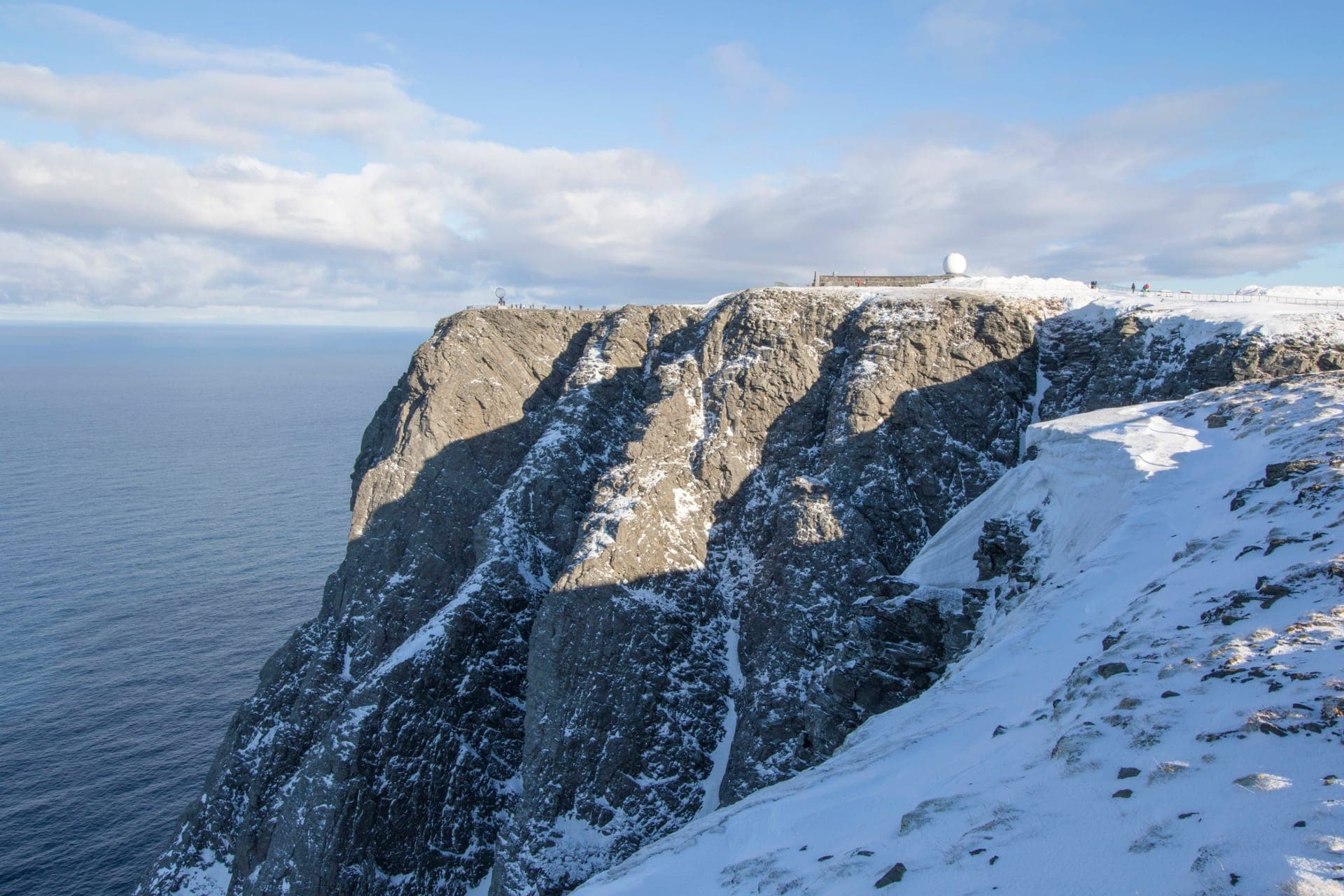 Das verschneite Nordkap-Plateau mit Globus-Monument und Radarkuppel über der steil zum Eismeer abfallenden Klippe