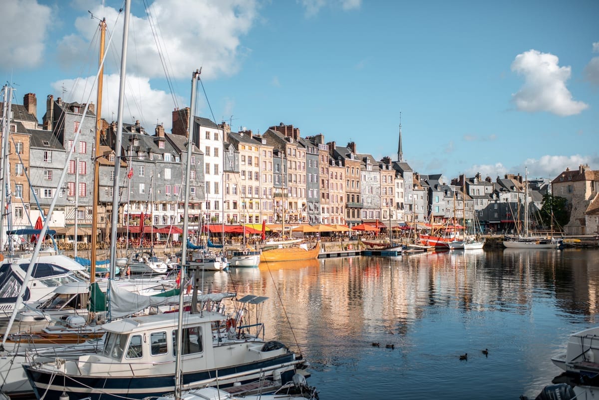 Der alte Hafen Vieux Bassin in Honfleur mit schmalen Häuserfassaden, die sich im Wasser spiegeln, Boote im Vordergrund