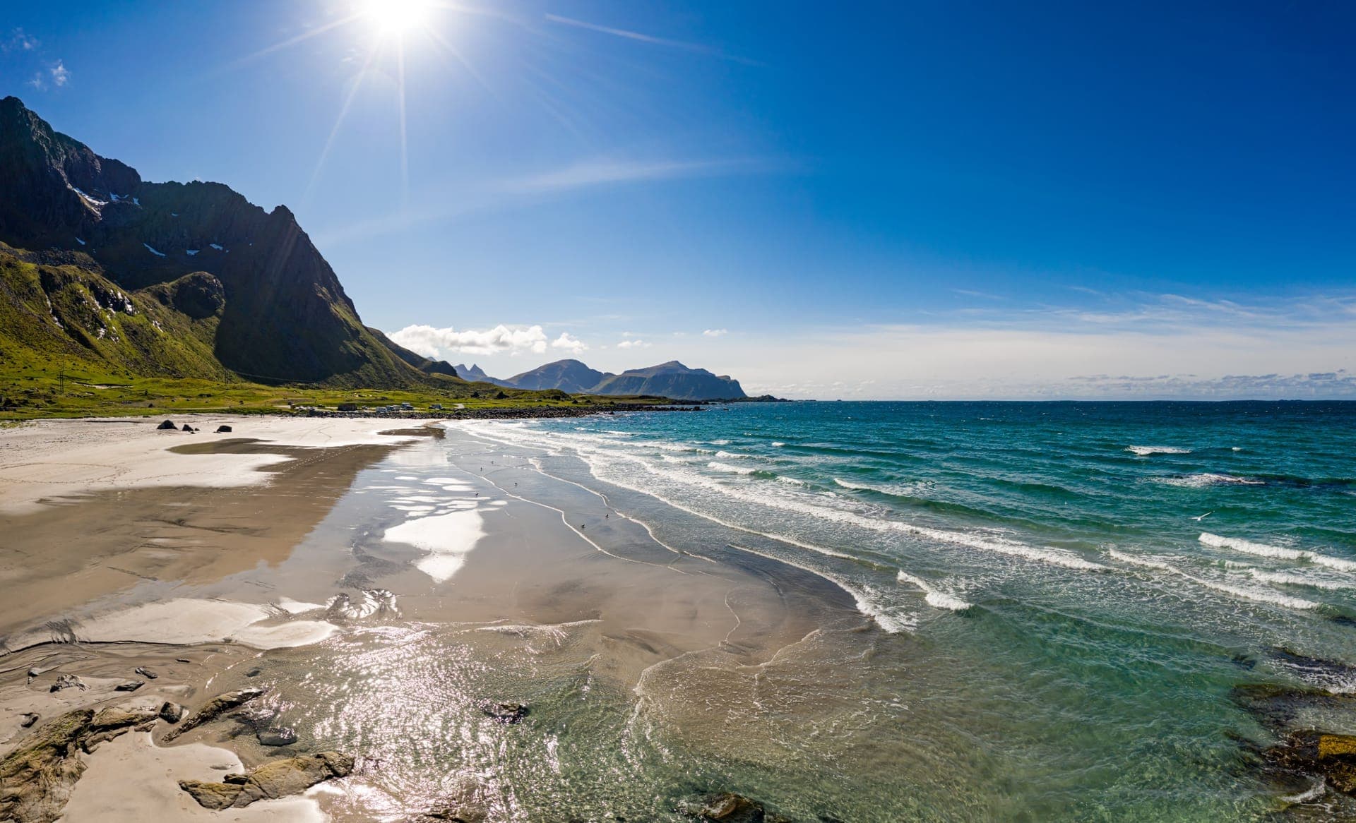Weißer Sandstrand von Haukland auf den Lofoten mit türkisblauem Wasser und steilen Bergen