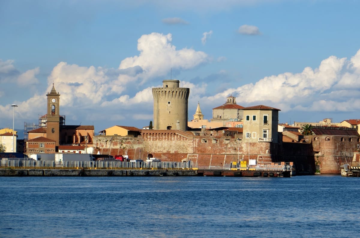 Blick vom Wasser auf Livorno mit dem runden Mastio di Matilde der Fortezza Vecchia und den Kirchtürmen der Altstadt