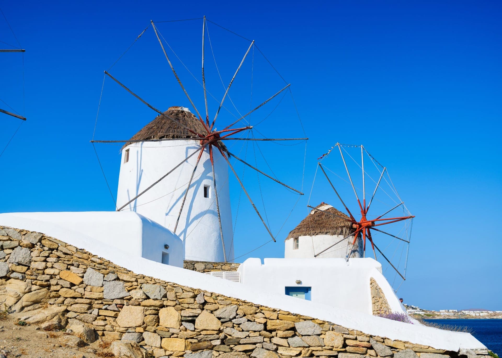 Die Windmühlen von Kato Mili oberhalb der weißen Häuser von Mykonos-Stadt mit dem Meer im Hintergrund
