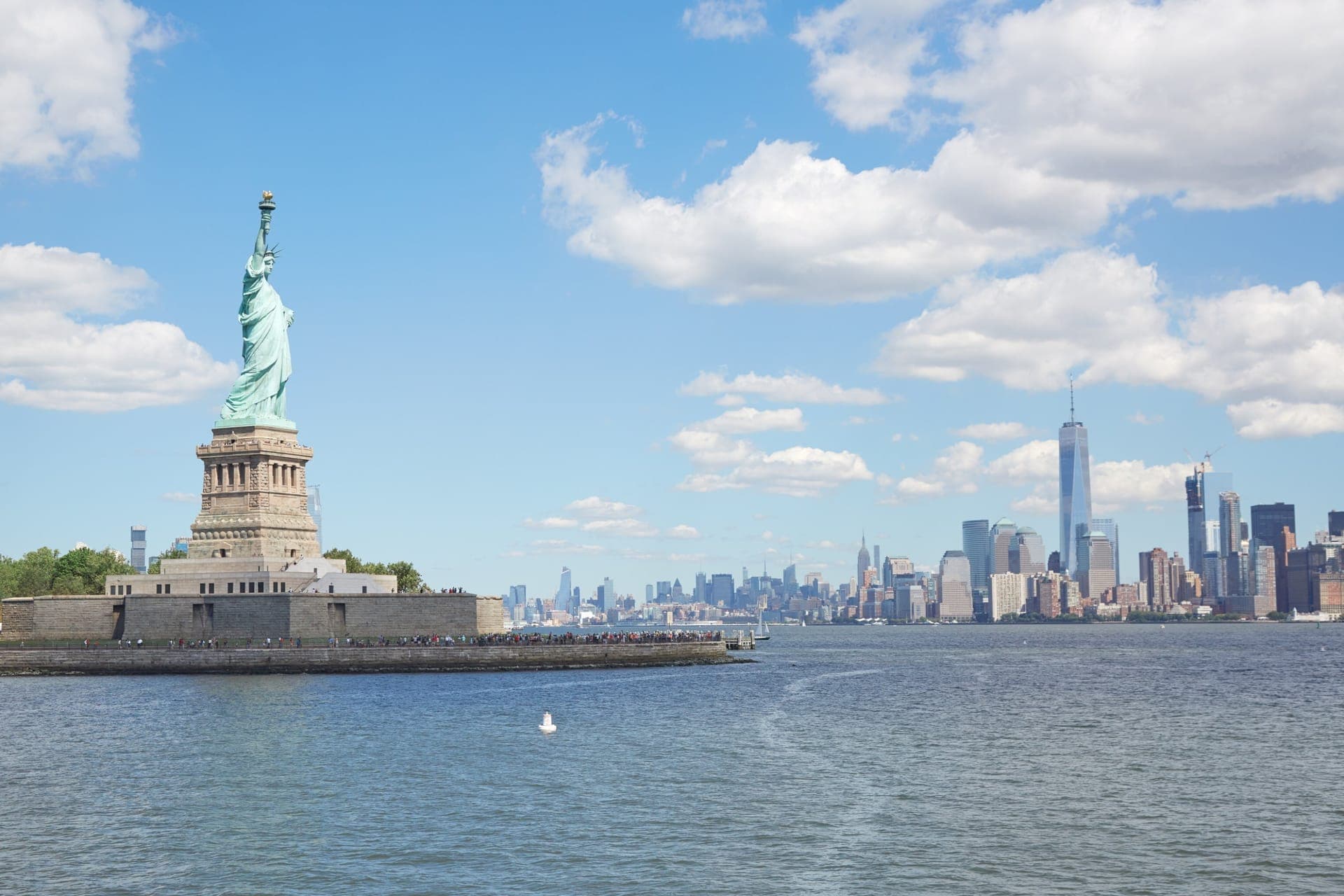 Kreuzfahrtschiff passiert bei Sonnenaufgang die Freiheitsstatue vor der Skyline von Manhattan