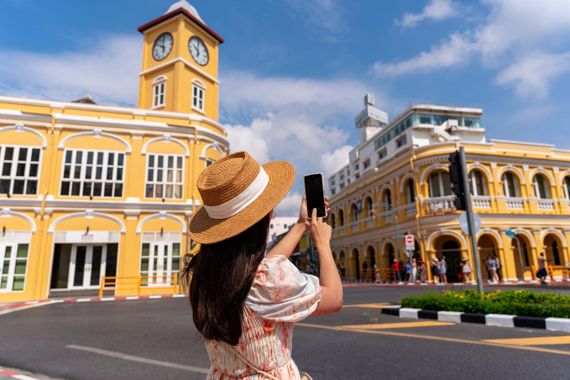 Gelbe Sino-Portugiesische Häuserzeile mit Uhrturm in der Altstadt von Phuket Town unter blauem Himmel