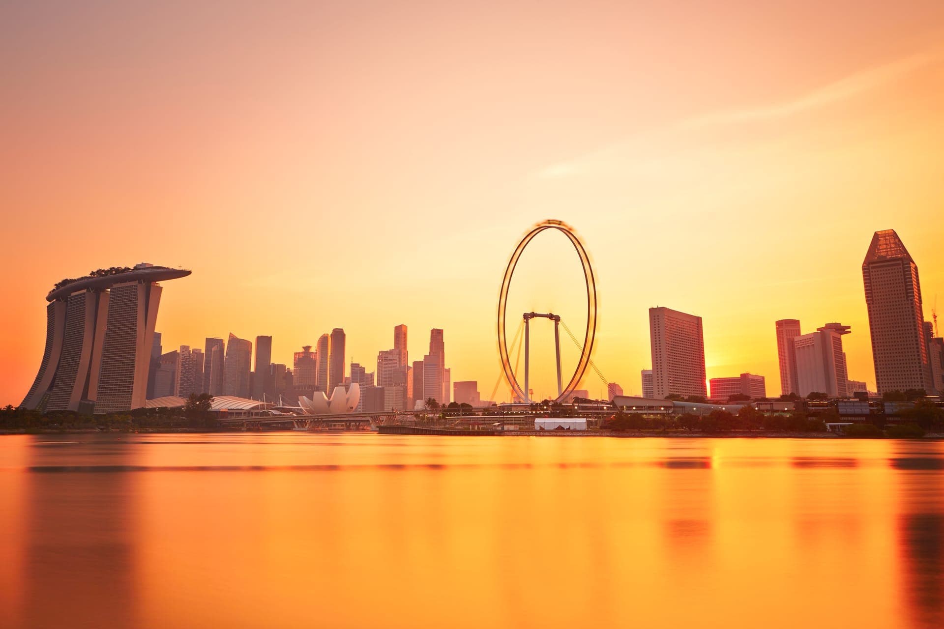 Skyline von Singapur bei Sonnenuntergang, die Hochhäuser spiegeln sich im Wasser der Marina Bay