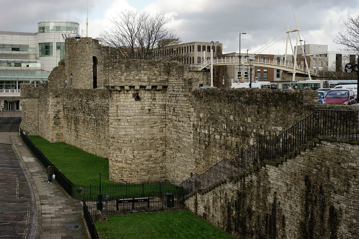 Erhaltener Abschnitt der mittelalterlichen Stadtmauer von Southampton mit rundem Wehrturm, dahinter moderne Bürogebäude und ein Einkaufszentrum
