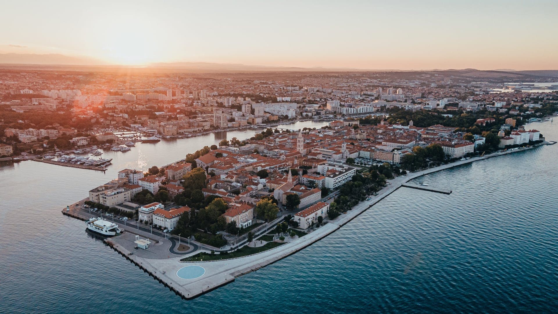Die Altstadt-Halbinsel von Zadar aus der Luft im Abendlicht, umgeben von Hafenbecken und Adria