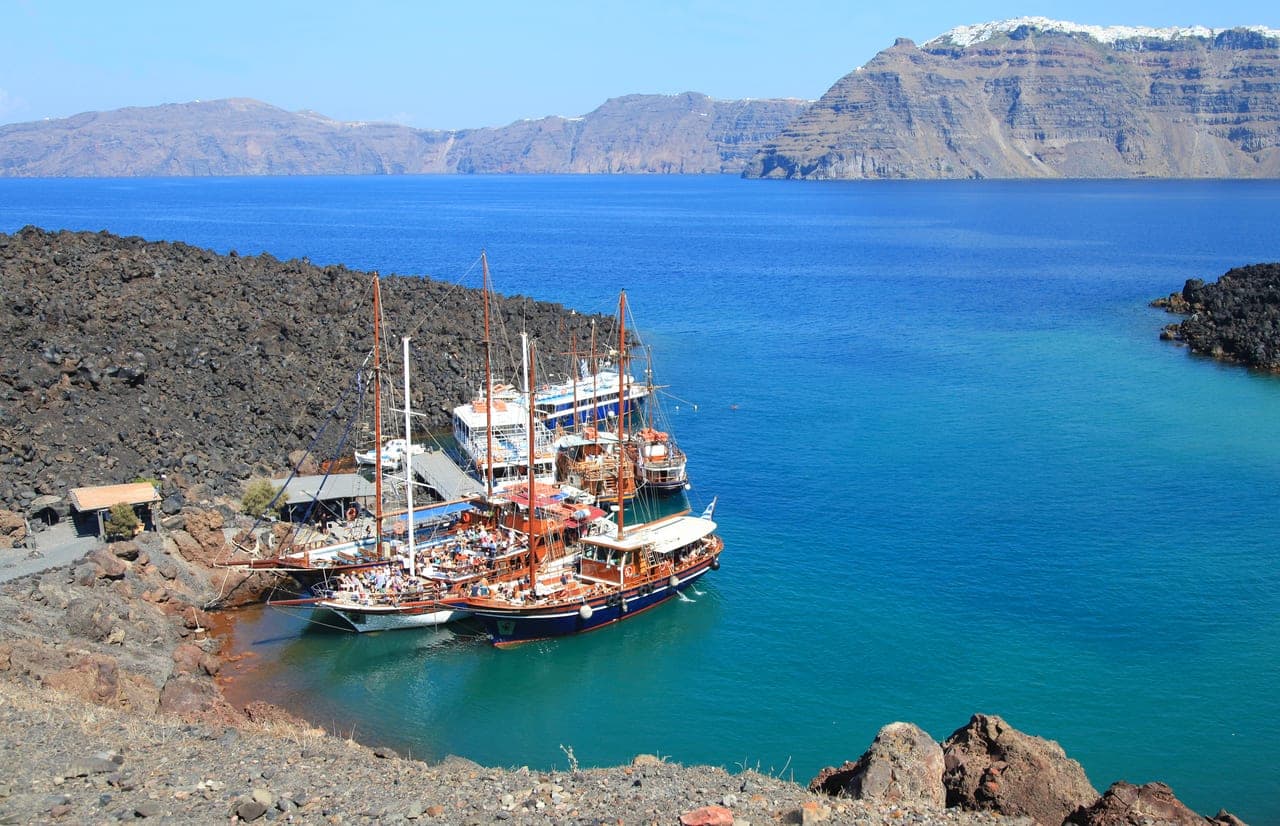 Ausflugsboote im Alten Hafen von Santorini unterhalb der steilen Caldera-Wand