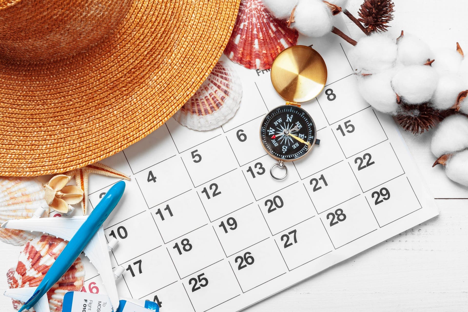 Reiseplanung mit Kalender, Kompass, Sonnenhut und Flugtickets