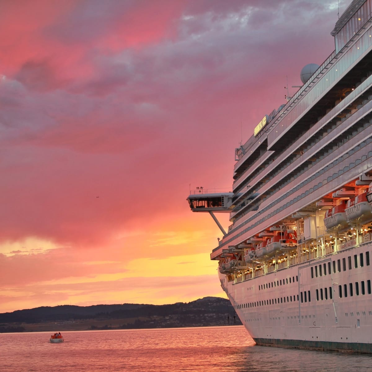 Kreuzfahrtschiff läuft bei Sonnenuntergang in einen Hafen ein