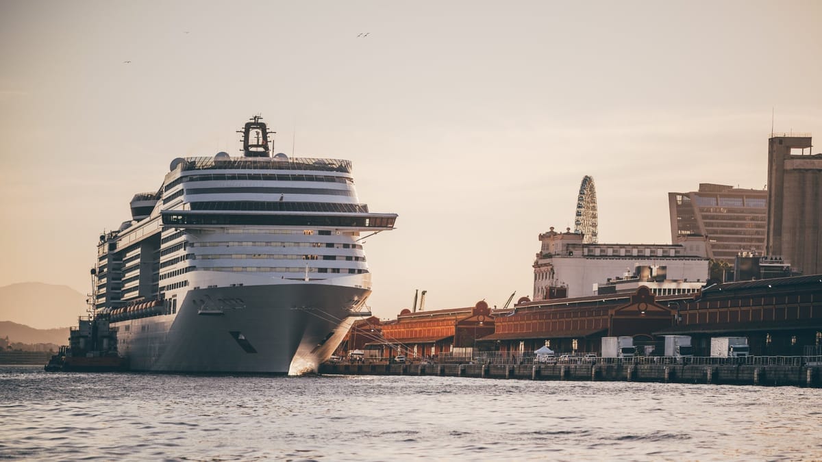 Großes Kreuzfahrtschiff liegt direkt am Kai einer Hafenstadt bei Sonnenuntergang
