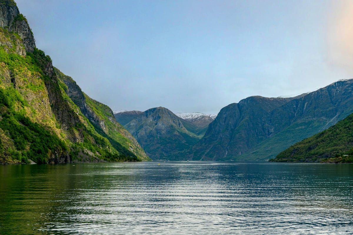Steile Bergflanken über dem ruhigen Wasser des Nærøyfjords