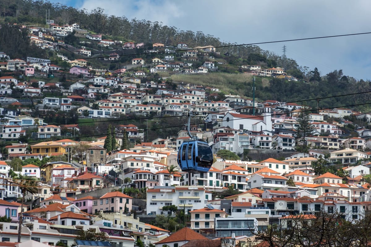 Eine Gondel der Seilbahn nach Monte über den Dächern von Funchal mit Blick auf die Bucht