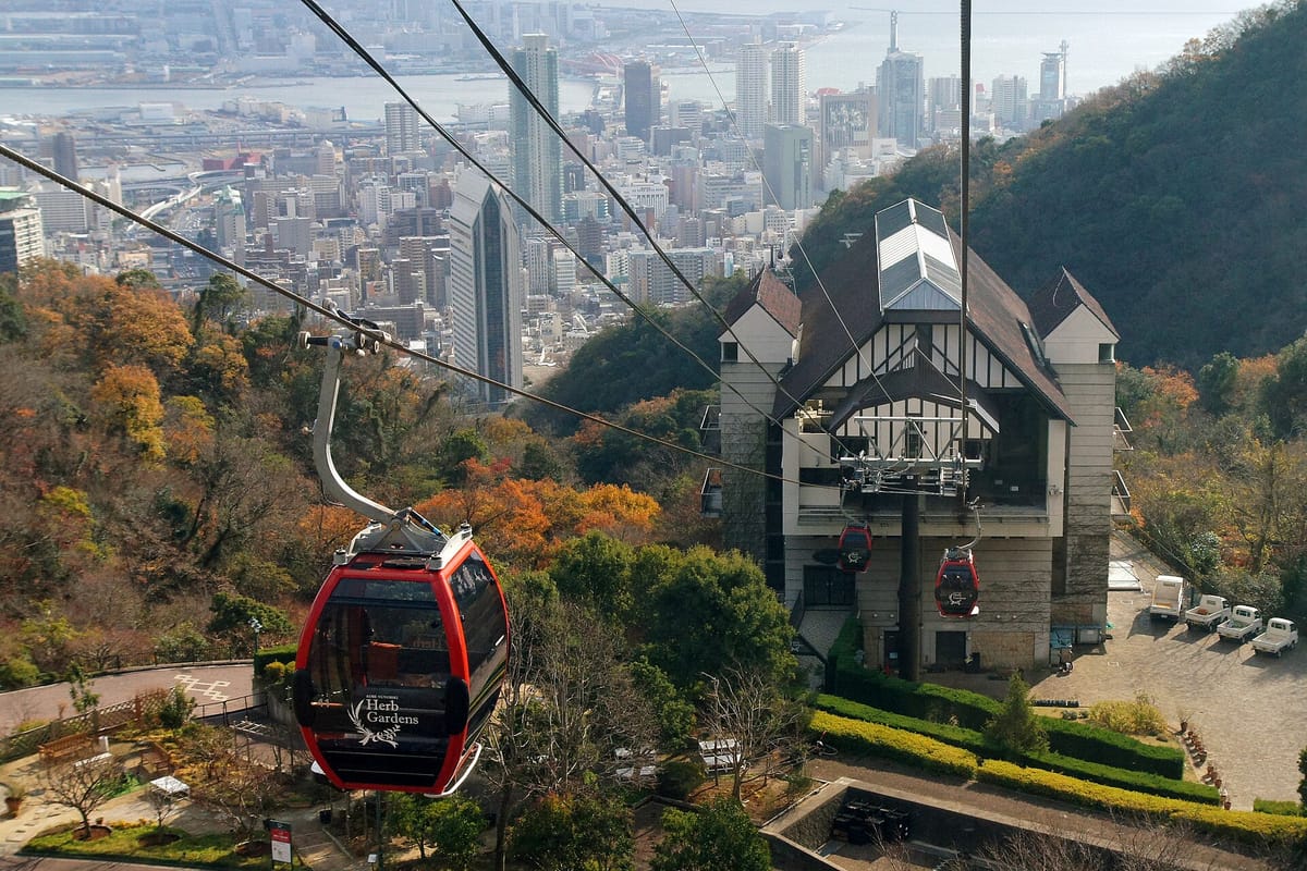 Gondel der Shin-Kobe Ropeway über dem grünen Nunobiki-Kräutergarten mit Panoramablick auf Kobe und den Hafen
