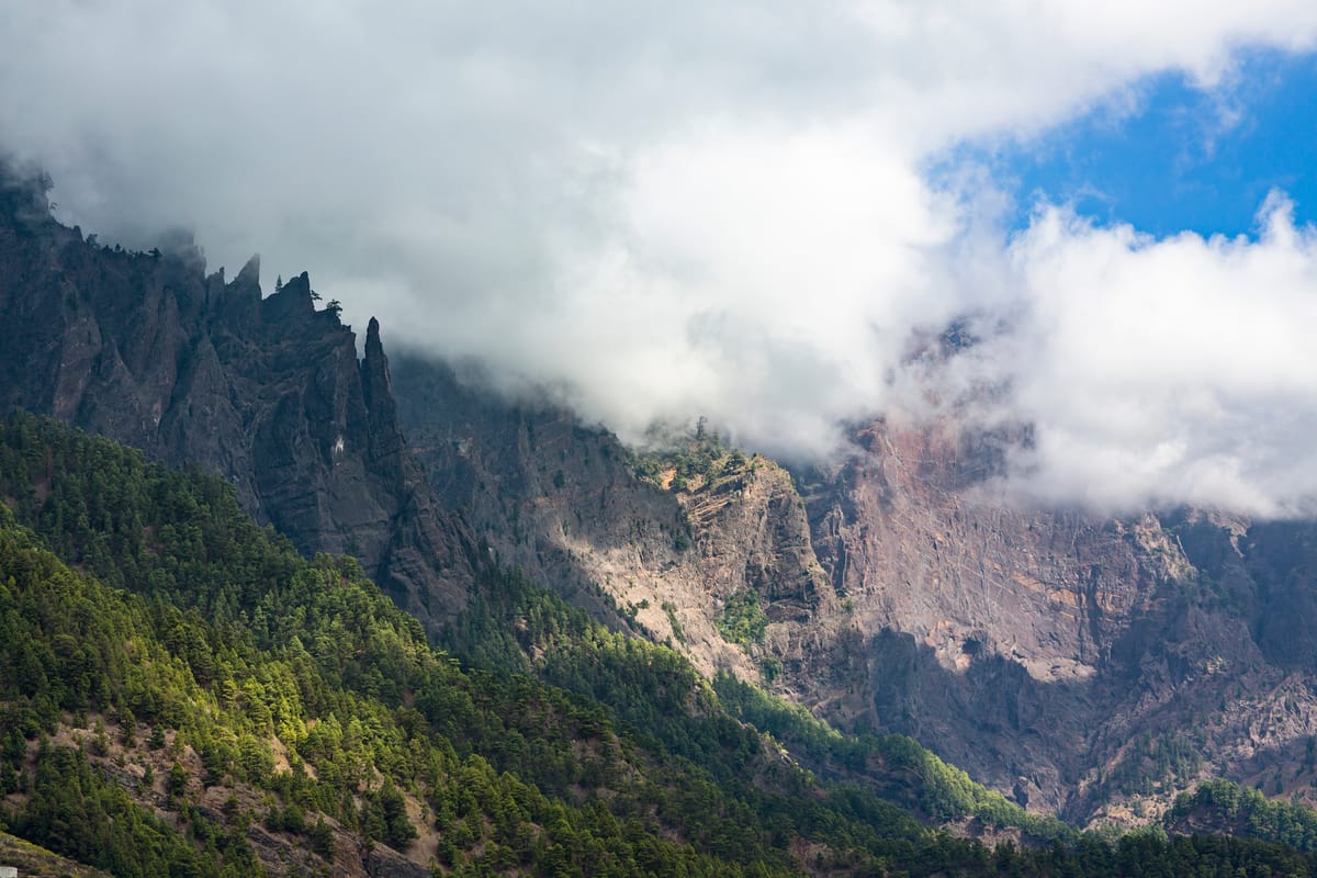 Zerklüftete Bergkämme der Caldera de Taburiente auf La Palma, teilweise von Wolken verhangen, mit grünen Kiefernhängen