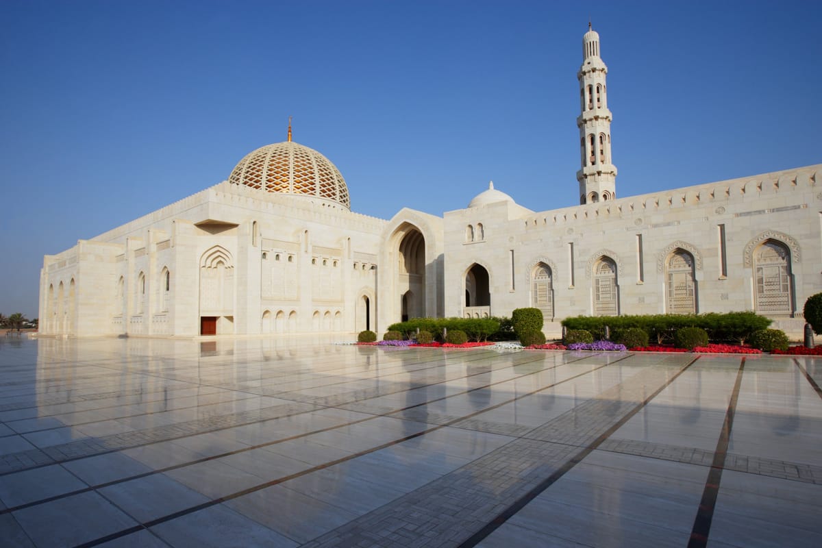 Weiße Marmorarkaden und Minarett der Großen Sultan-Qabus-Moschee in Muscat