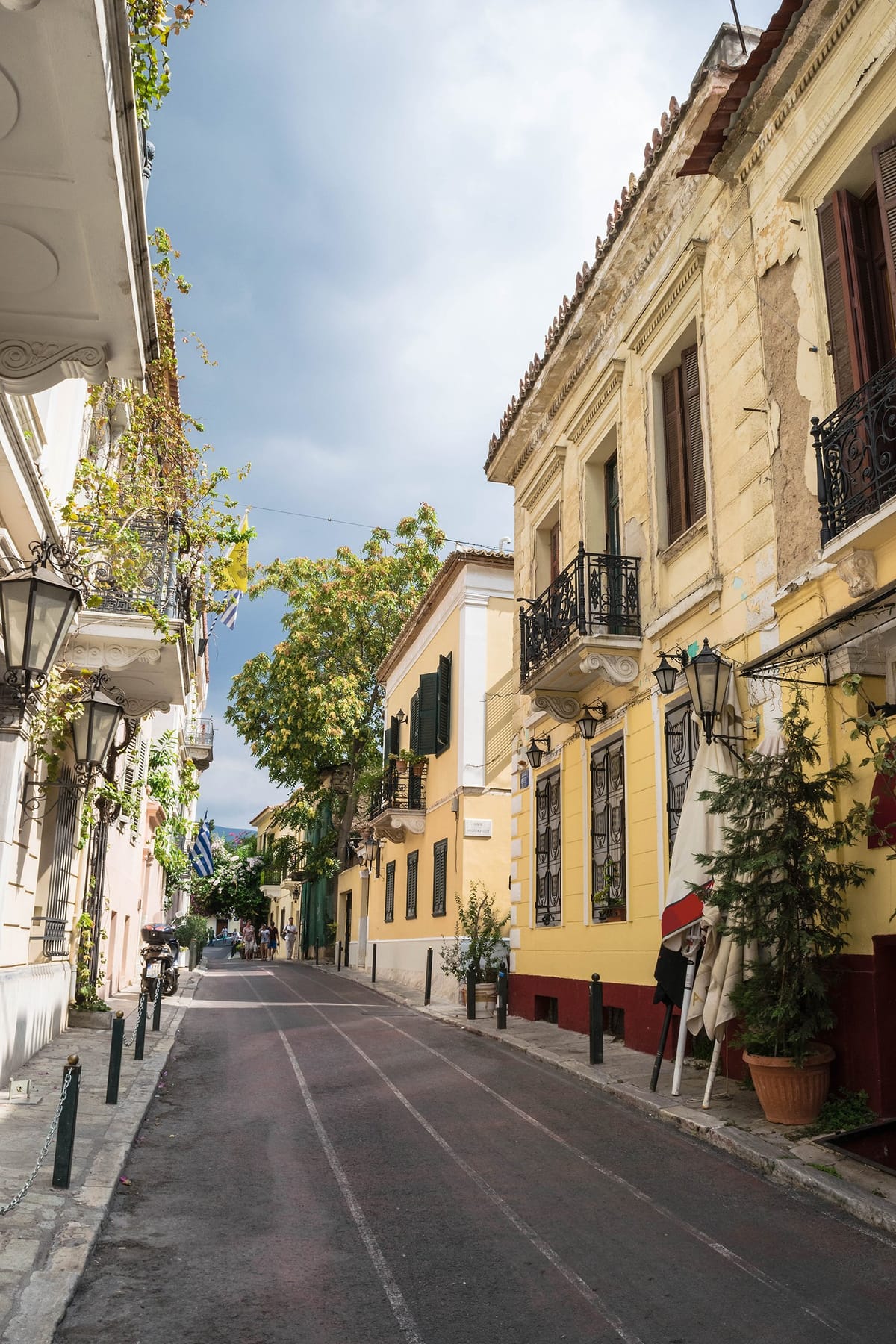 Enge Gasse im Athener Altstadtviertel Plaka mit Tavernen und dem Akropolis-Felsen im Hintergrund