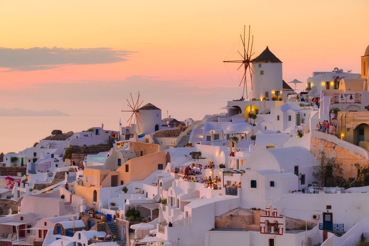 Sonnenuntergang über Oia mit den historischen Windmühlen und weißen Häusern