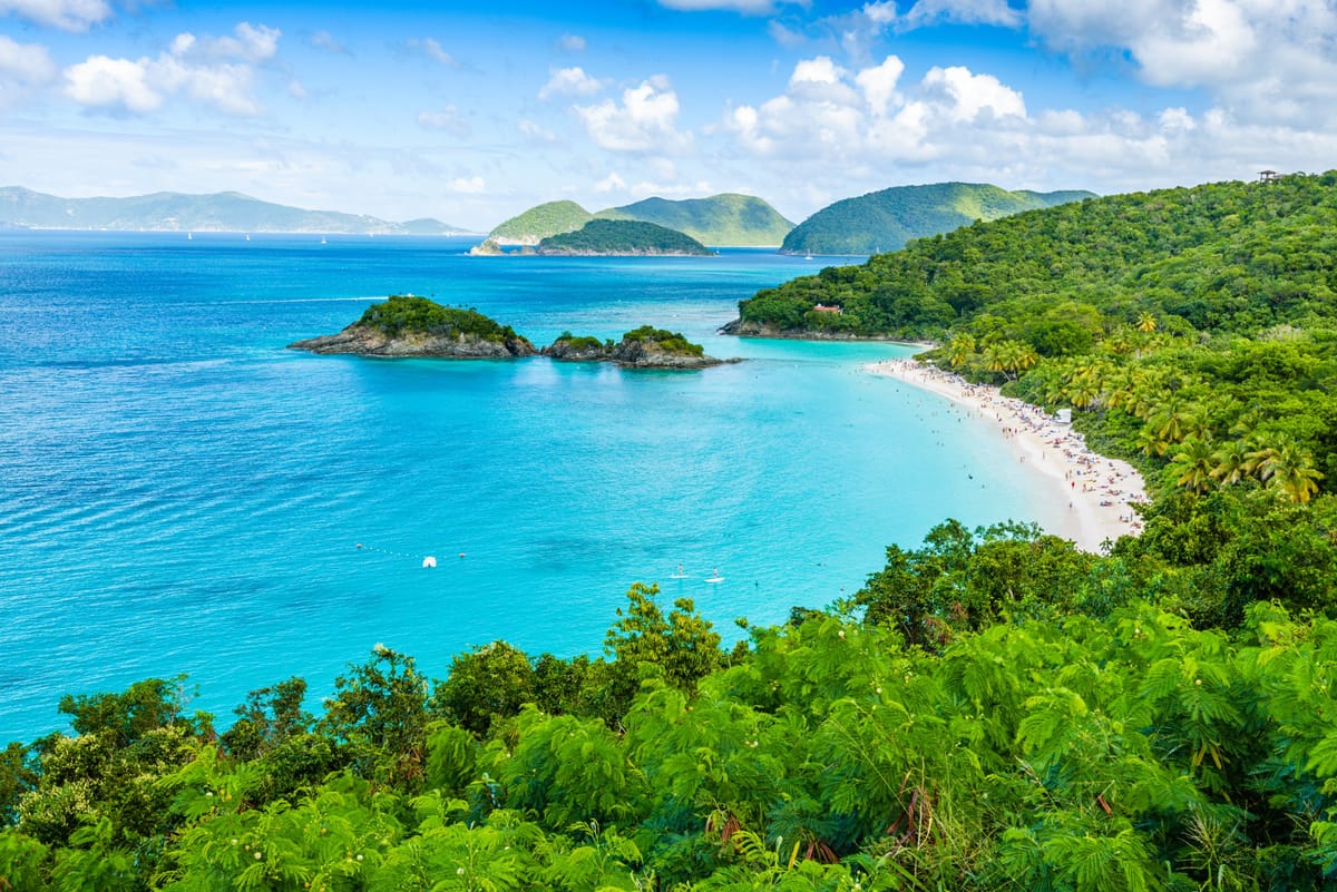 Blick auf die Trunk Bay auf St. John mit weißem Sand, vorgelagerten Inseln und Schnorchlern im klaren Wasser