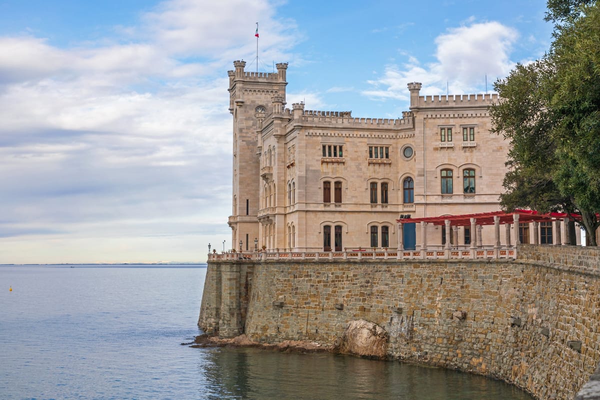 Weißes Schloss Miramare auf der Felsklippe über der blauen Adria mit Parkanlage