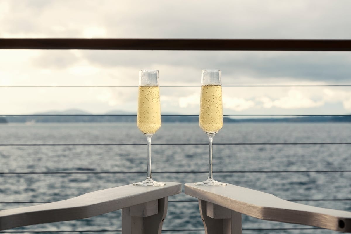 Zwei Gläser Champagner auf dem Geländer eines Kreuzfahrtschiffs mit Meerblick