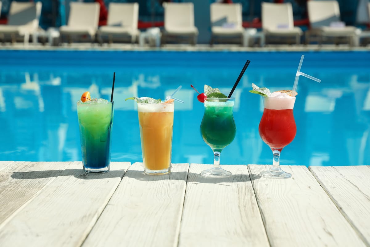 Bunte Cocktails auf einer Holzterrasse nahe dem Pool